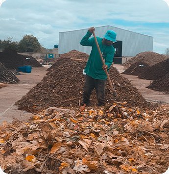Colaborador manejando leira de compostagem com resíduos verdes